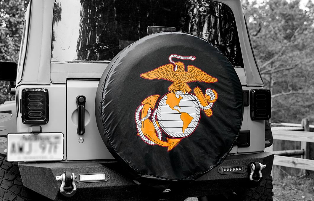 Back of jeep showing a black spare tire cover with USMC EGA emblem